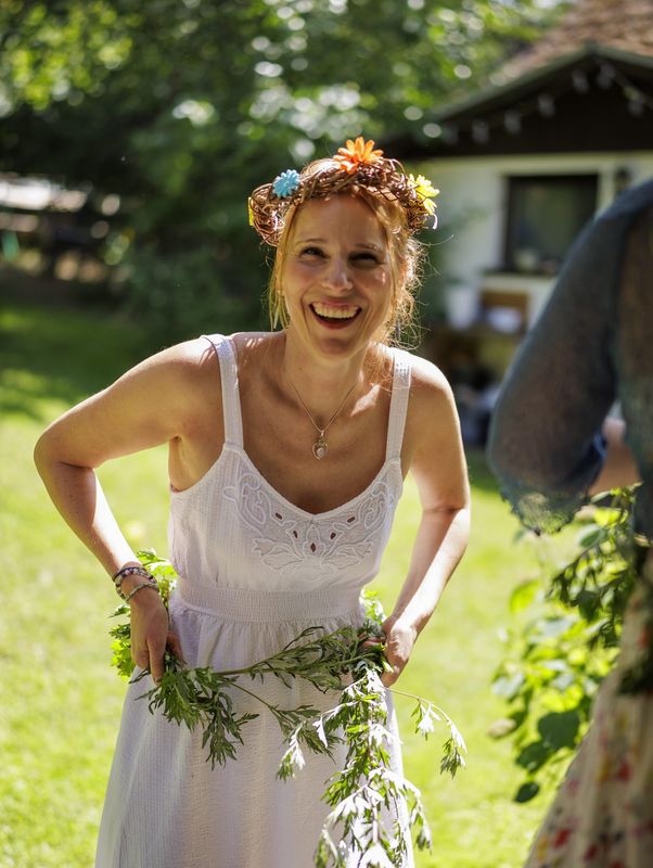 Lachende Teilnehmerin mit Blumenkranz und Grüngirlande
