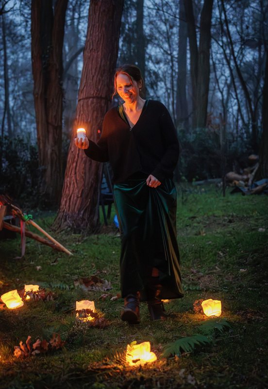 Melanie geht mit einer Kerze durch den Lichterkreis im Wald